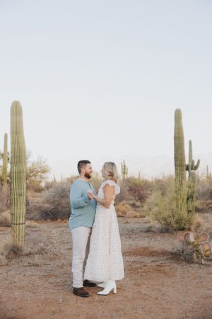A romantic desert engagement shoot featuring a couple surrounded by majestic saguaro cacti.
