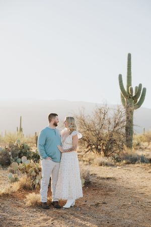 A romantic desert photoshoot featuring a couple in coordinated outfits against a backdrop of cacti.