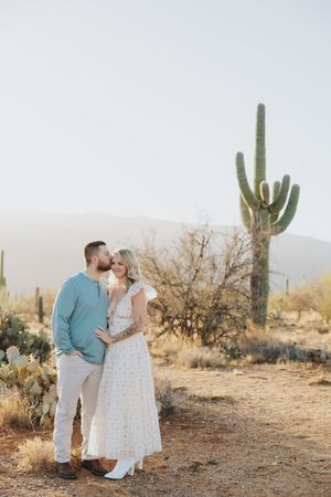 A tender moment between a couple in the Sonoran desert with saguaro cacti in the background.