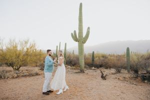 Romantic desert photoshoot with saguaro cacti and mountains in the background at golden hour.