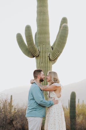 Romantic desert engagement photos with towering saguaro cactus framing the couple.