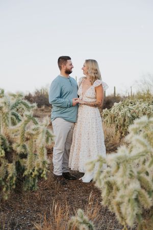 A romantic desert photoshoot featuring a couple posing among cholla cacti at sunset.