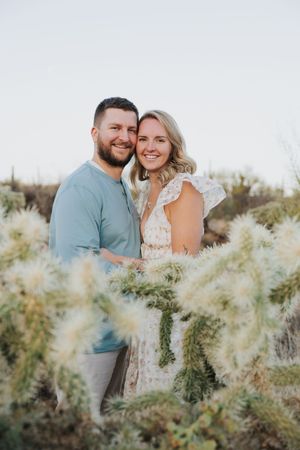 A joyful couple embraces while posing among desert flora.