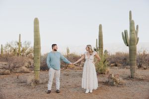 A romantic desert engagement session with towering saguaro cacti as backdrop.