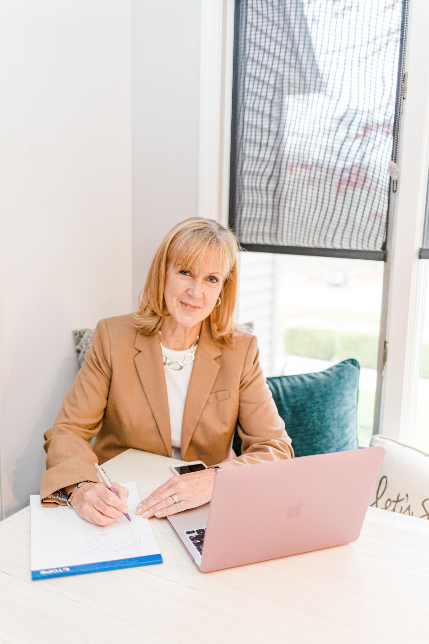 Hudson Valley realtor smiling with tan blazer, pink laptop smiling at camera during a branding photo shoot.