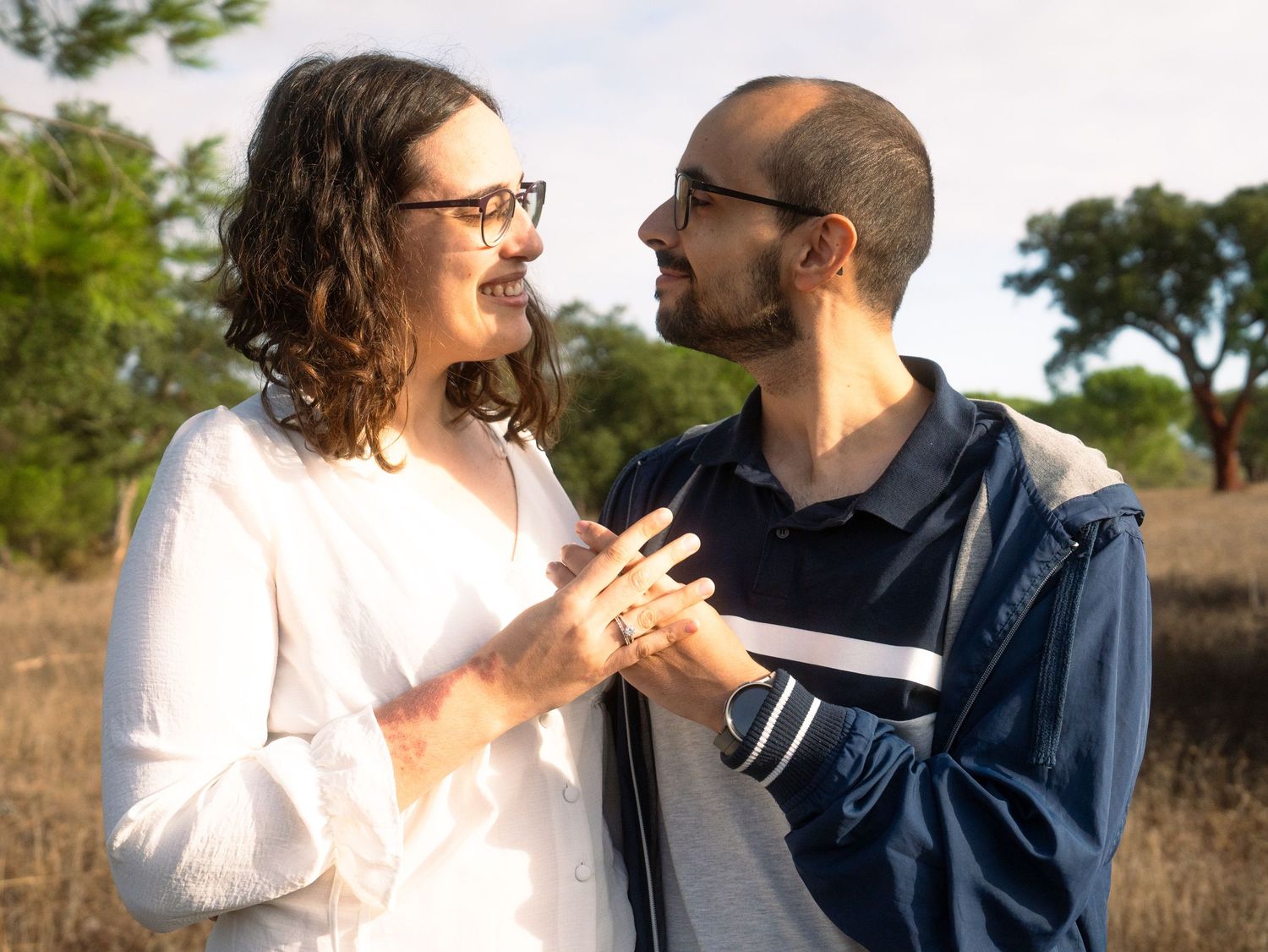 Couple in casual attire sharing a joyful moment outdoors in natural lighting.