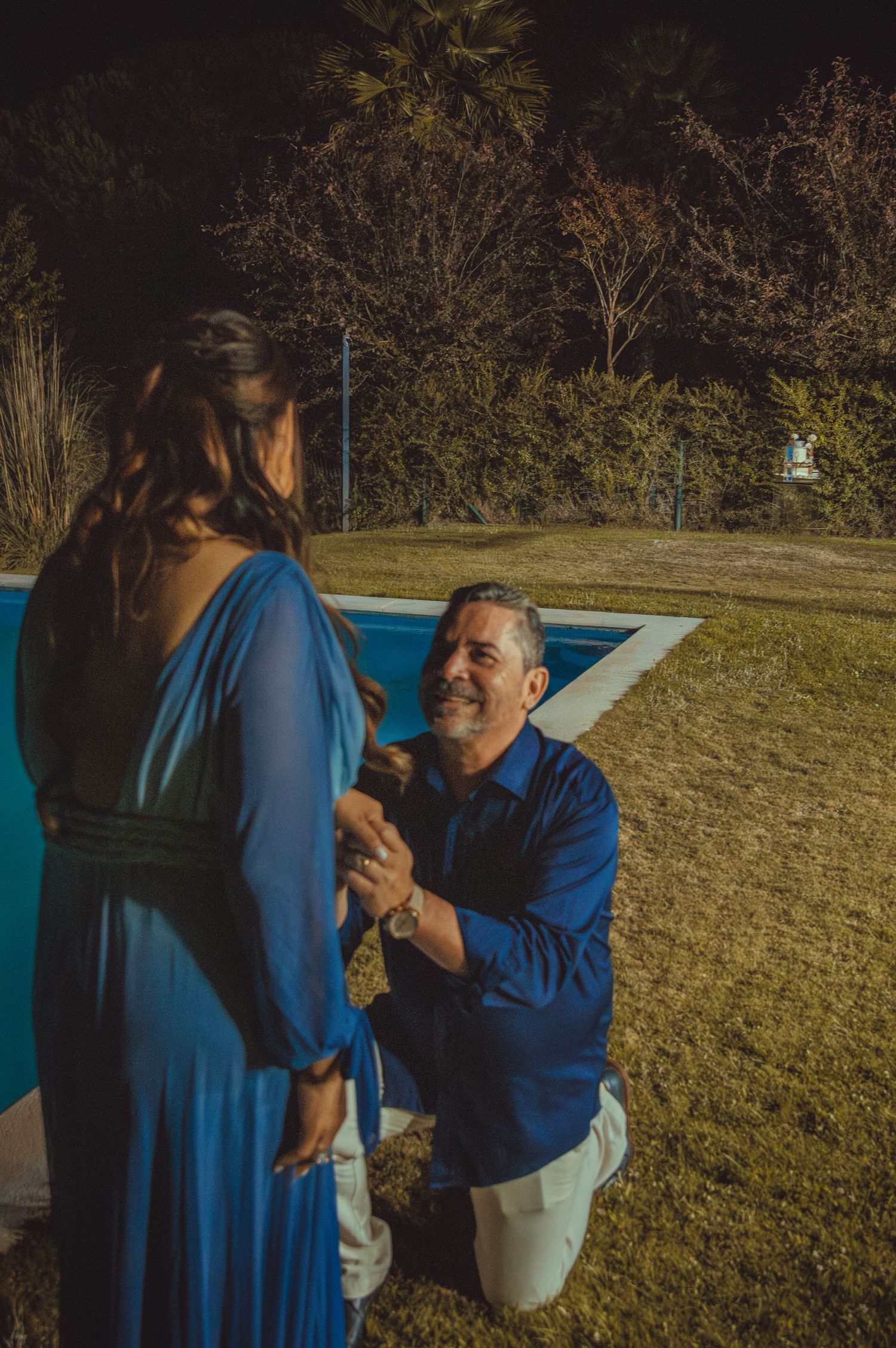 Couple in blue outfits sharing a tender moment outdoors during golden hour.