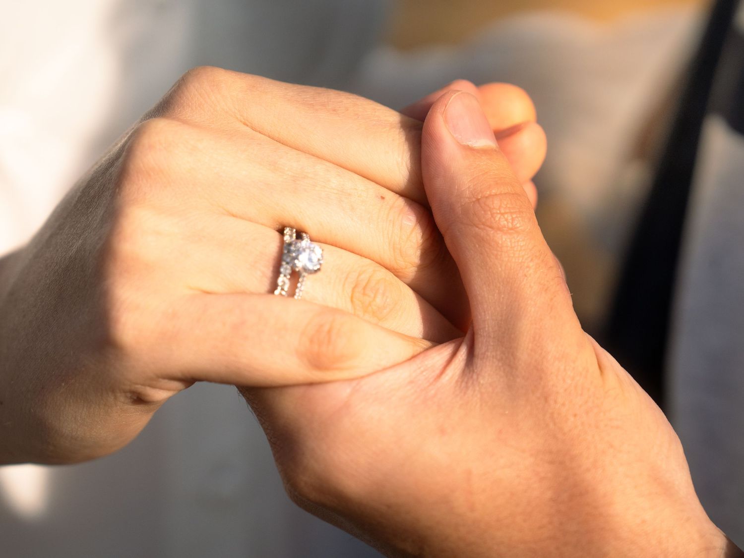 Close-up of hands showing off a new engagement ring in soft lighting.