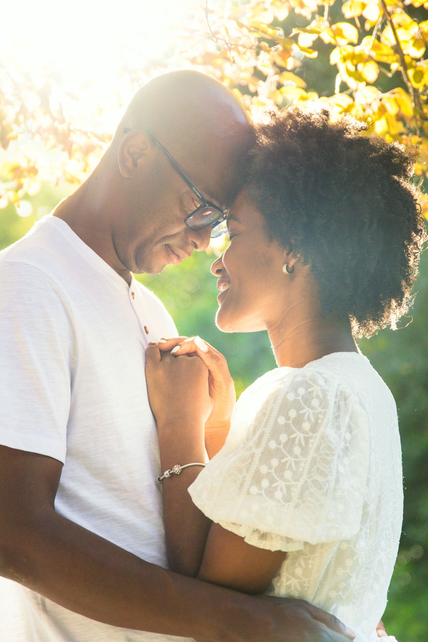 Romantic couple sharing an intimate moment at sunset with golden autumn leaves in the background.