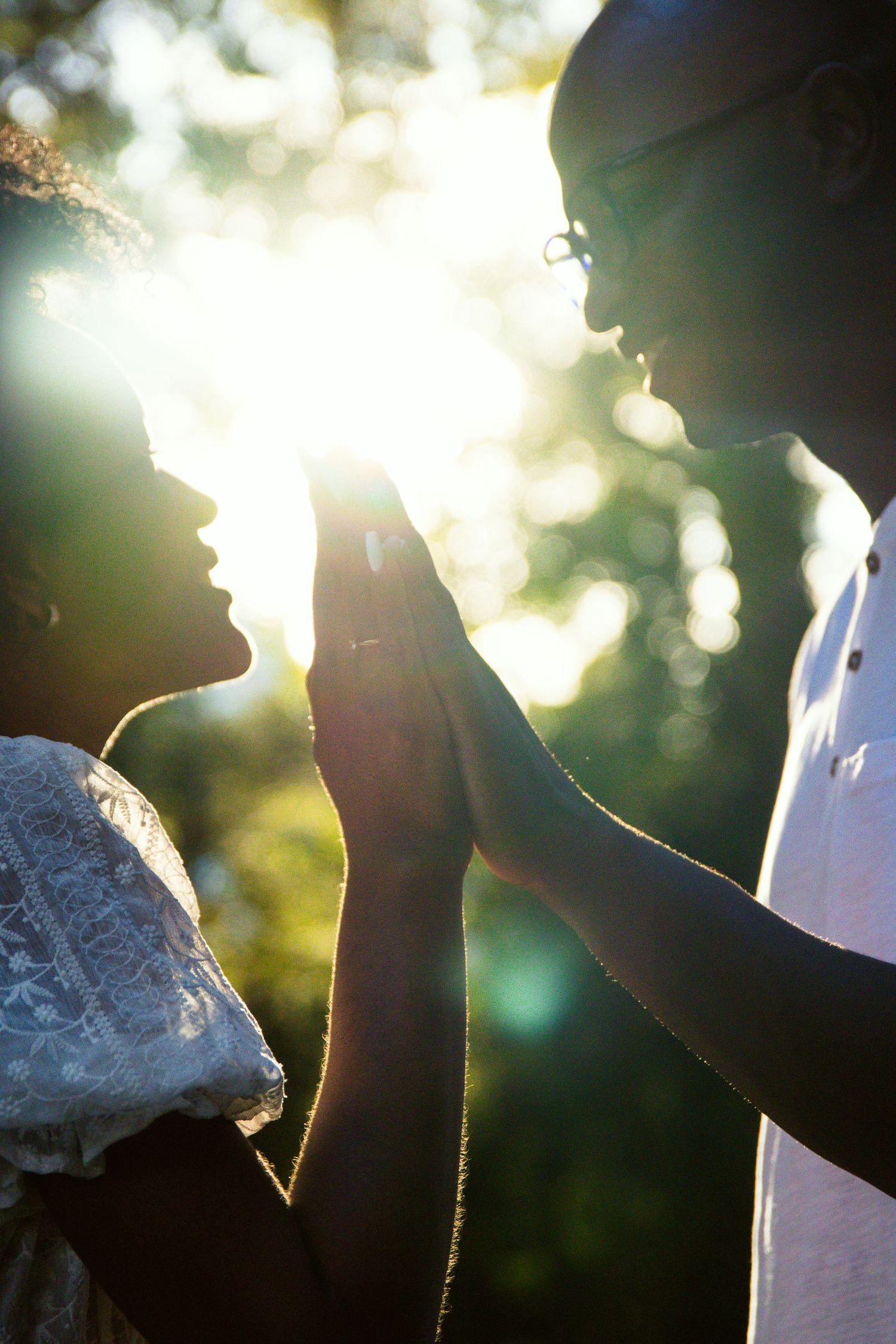 Artistic silhouette photograph with sun flares through trees creating dramatic lighting.