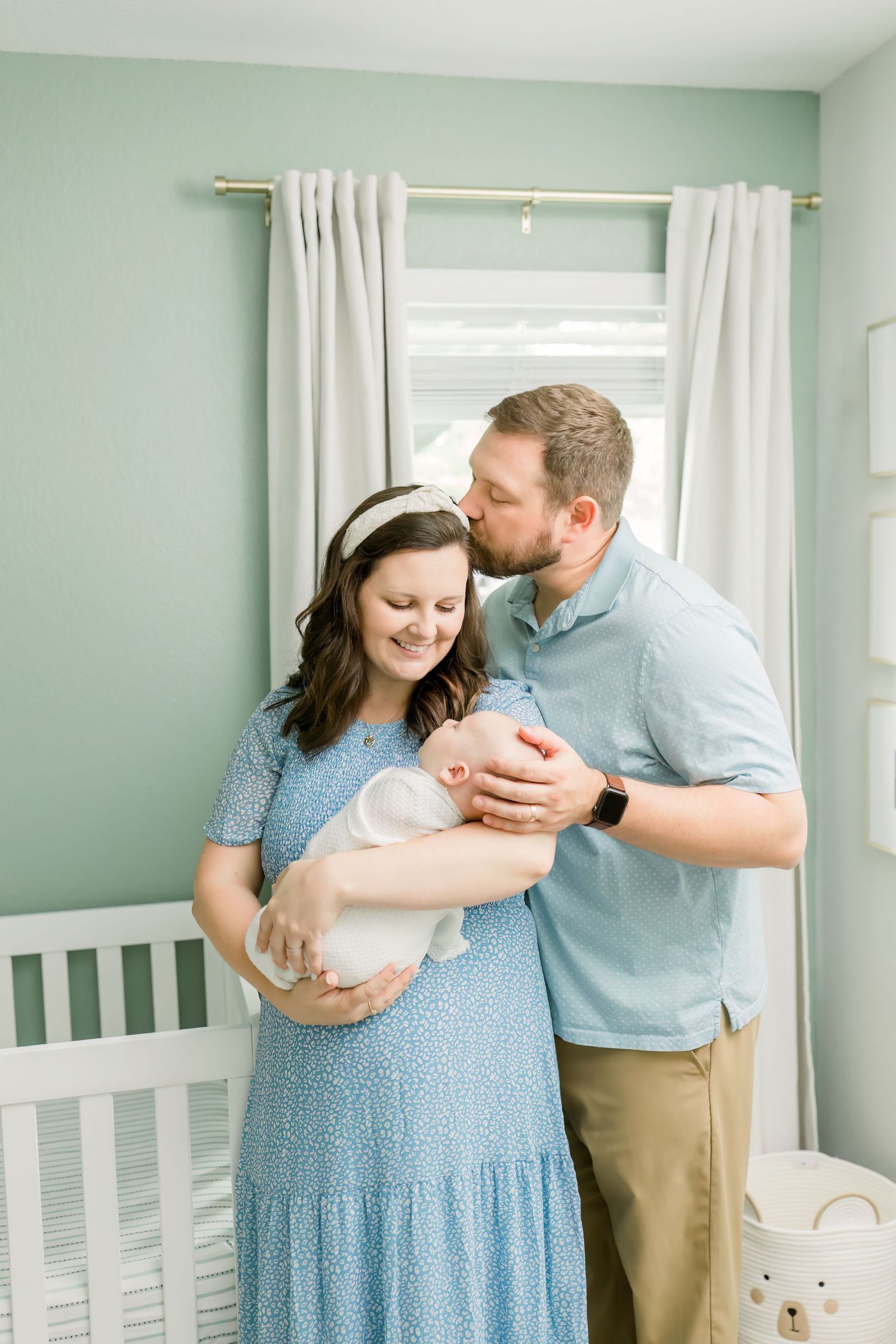 A sweet family moment shared in front of a window in a mint green nursery.