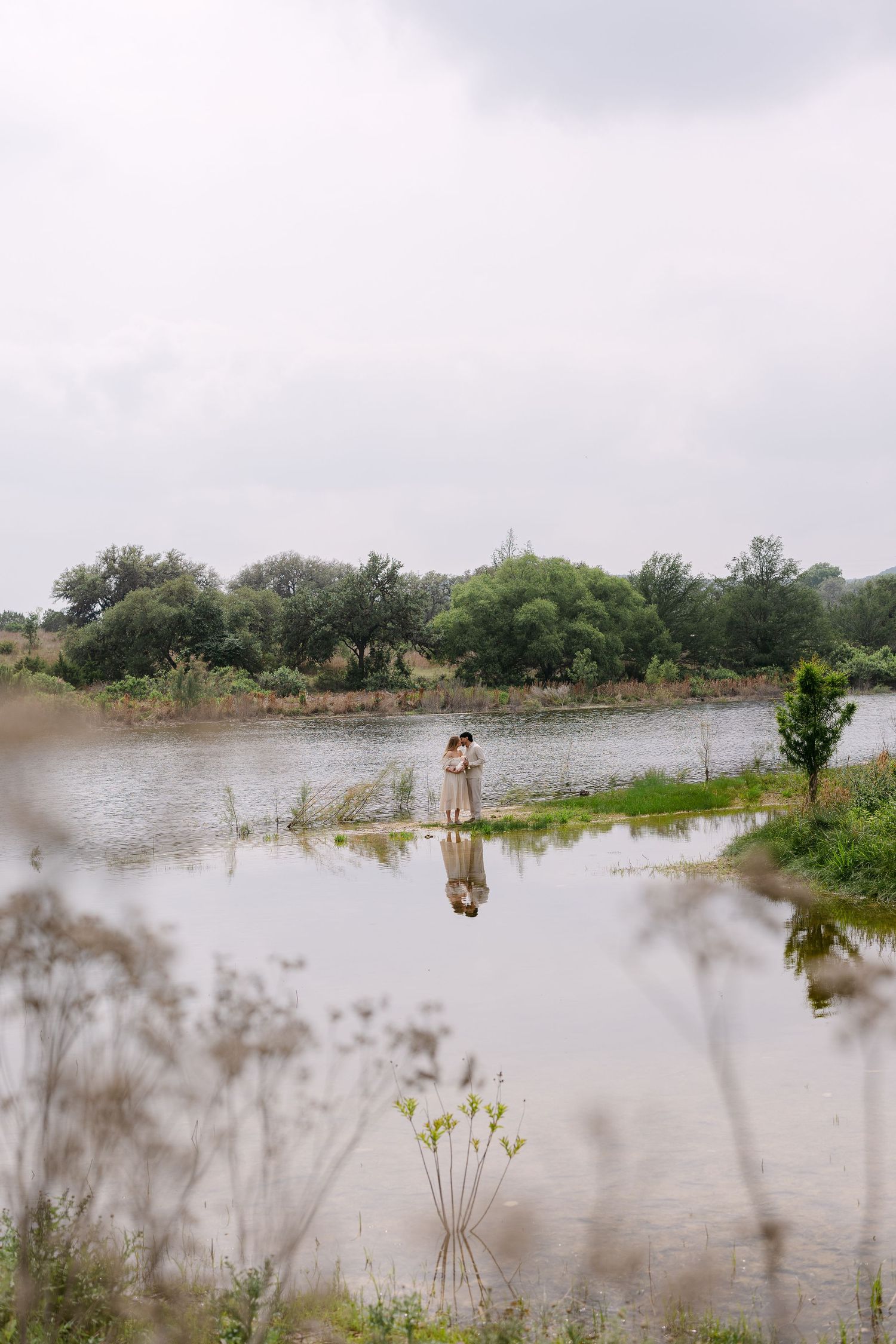 A couple stands back-to-back on a winding dirt path through tall grass.