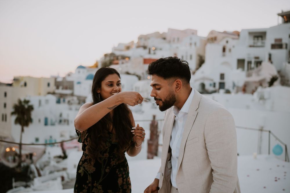 Celebratory moment between couple on scenic Santorini balcony at sunset.