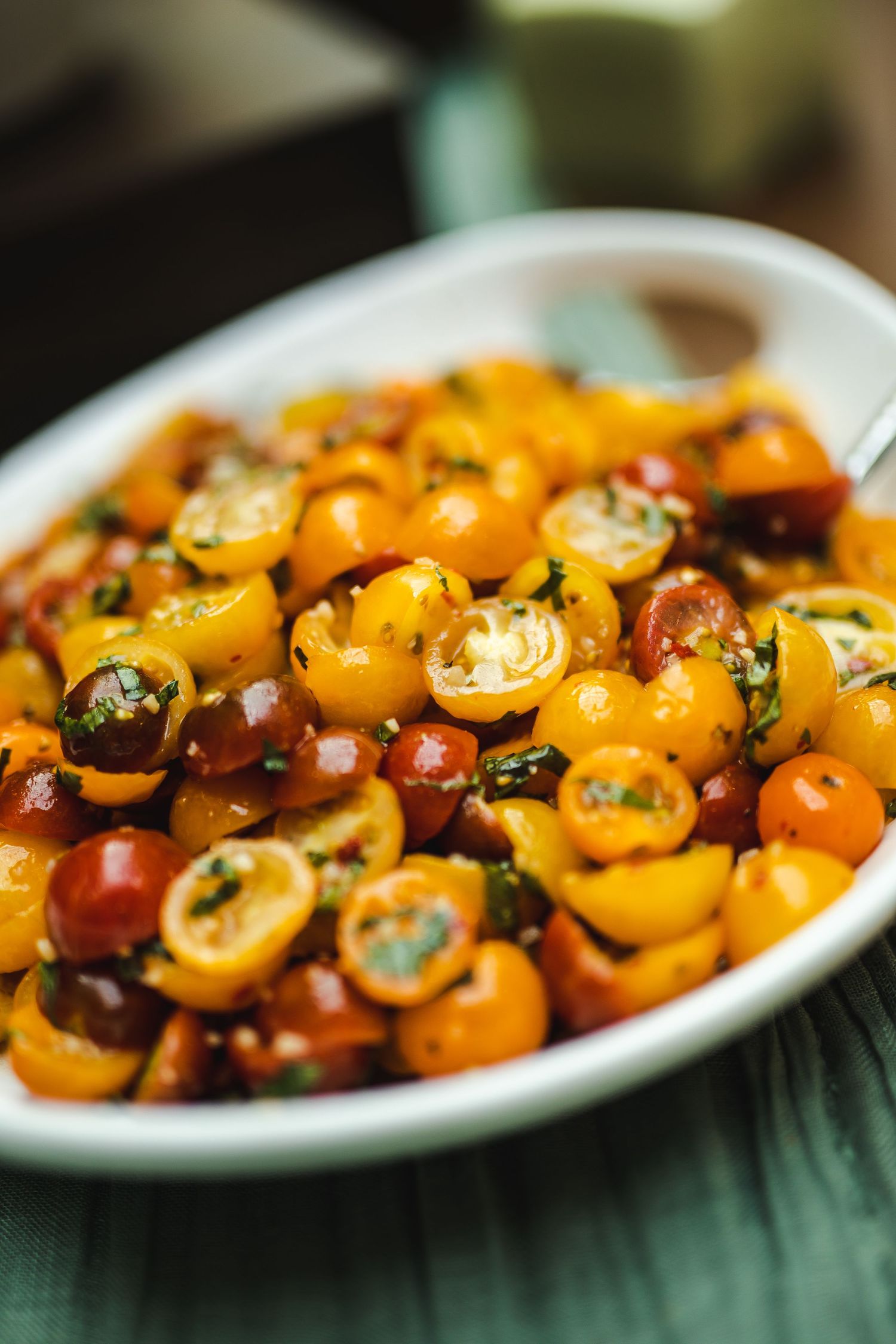 Colorful cherry tomato salad with herbs served in a white bowl.