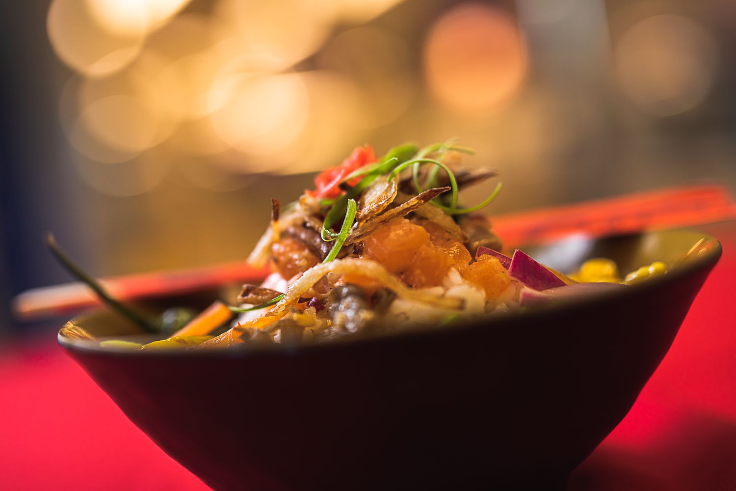 Gourmet Asian dish served in dark bowl with bokeh lighting effects.