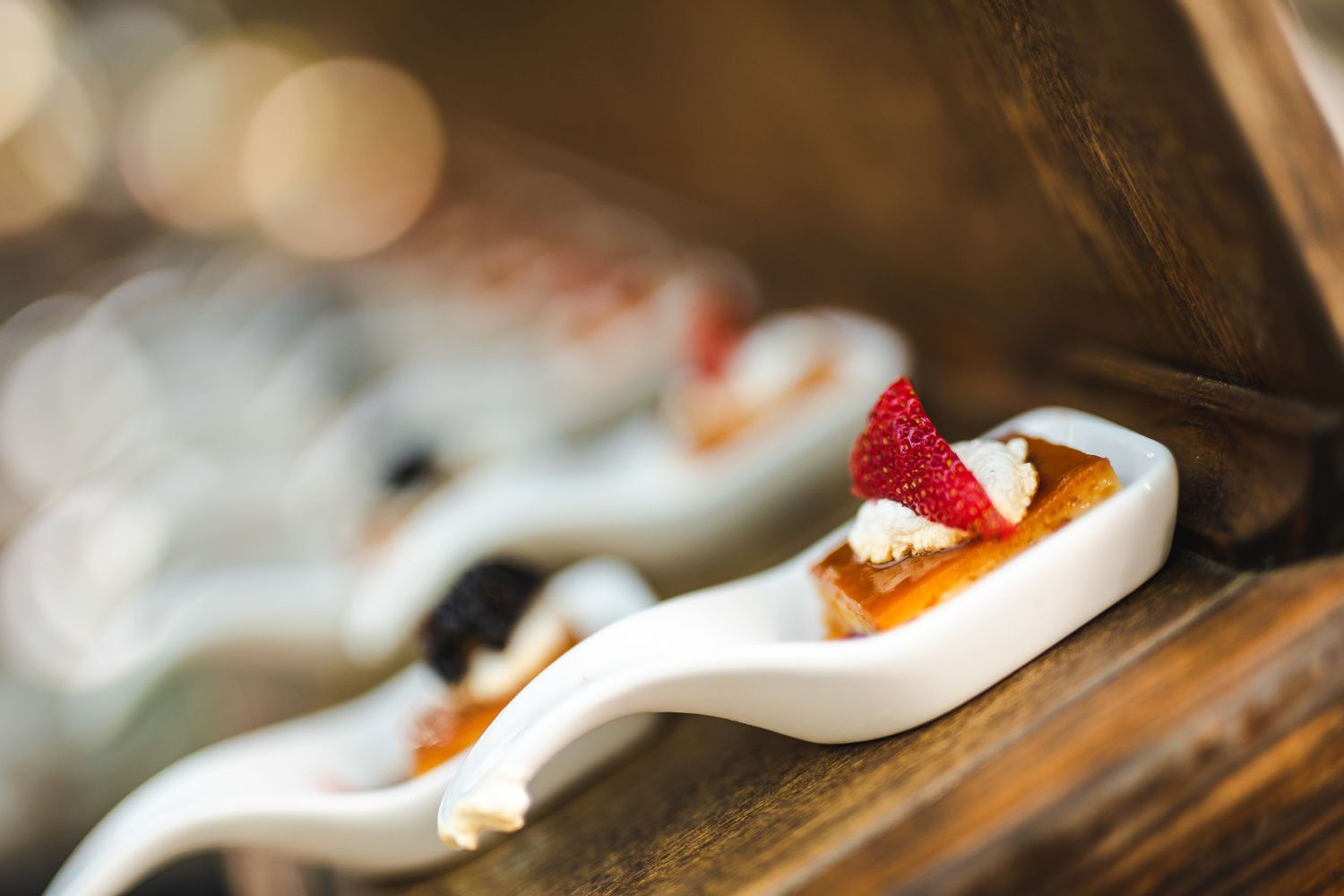 Artistic plating of a delicate appetizer with fresh fruit on a white ceramic spoon.