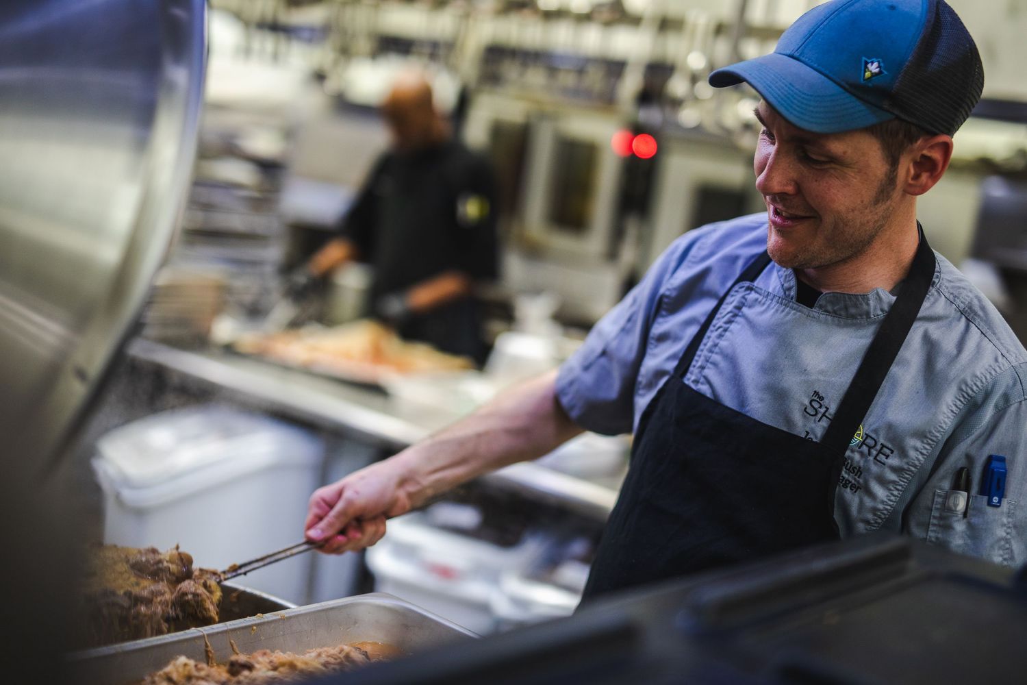 Kitchen staff preparing food at commercial cooking station.