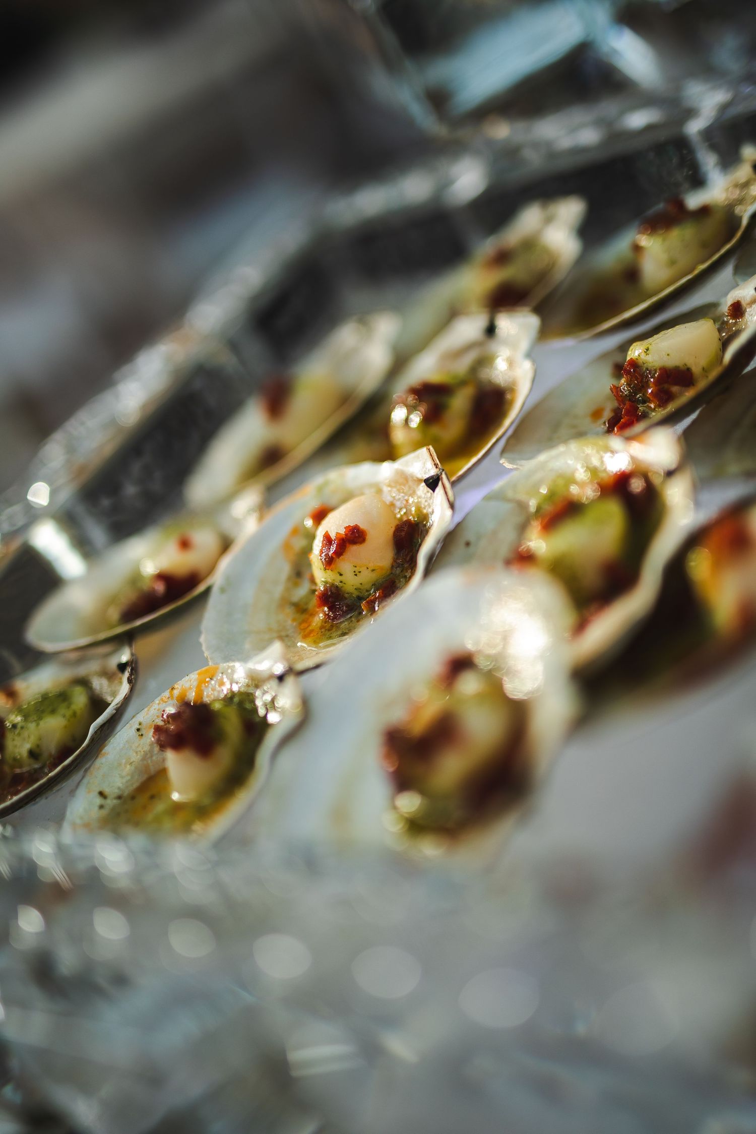 Close-up of elegant appetizers served in silver spoons with garnish.