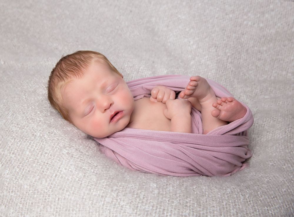 newborn baby photo posed in a pink wrap