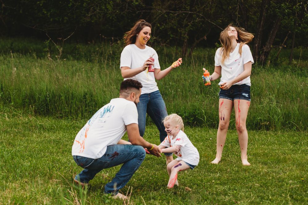 Playful outdoor paint activity with people in white shirts on green grass.