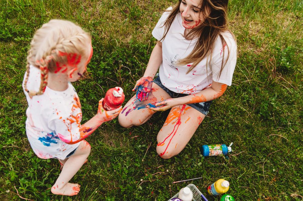 Paint bottles scattered on grass during outdoor activity.