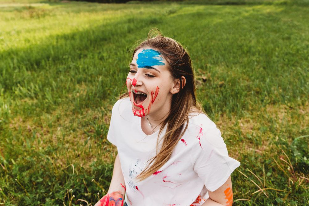 Playful scene of people having fun with colorful paint in a grassy outdoor setting.