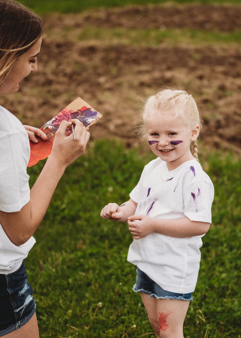 Paint-splattered clothing and faces during outdoor art activity.