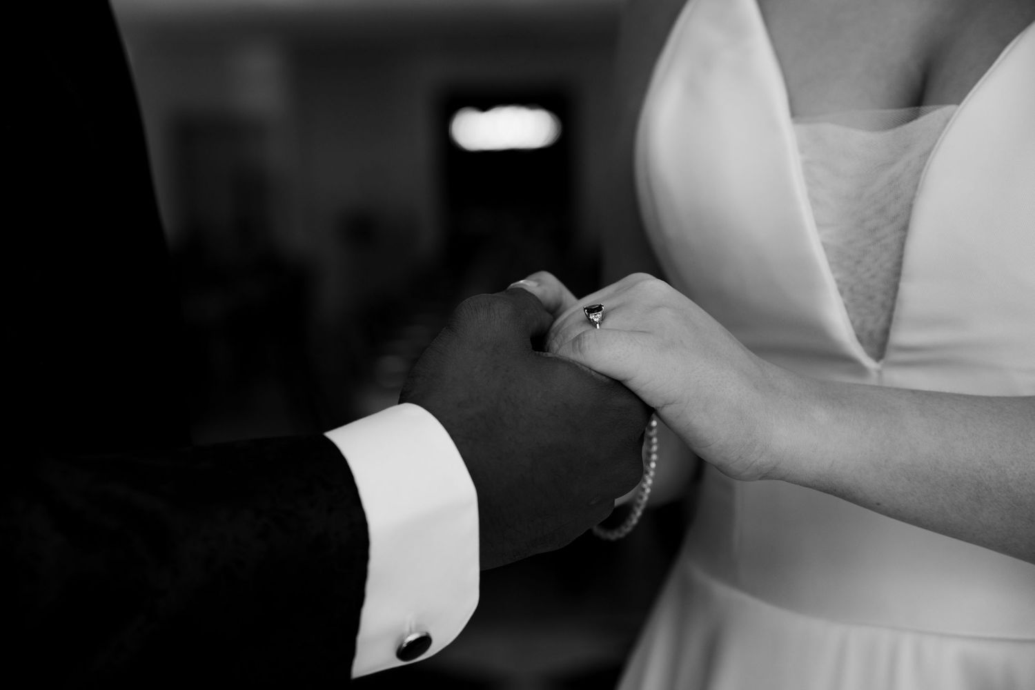 A black and white close-up of hands exchanging wedding rings during a ceremony.