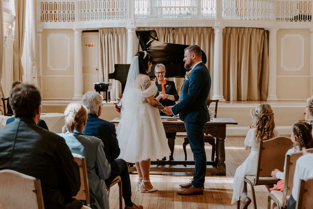 a bride and groom exchanging vows, holding hands.