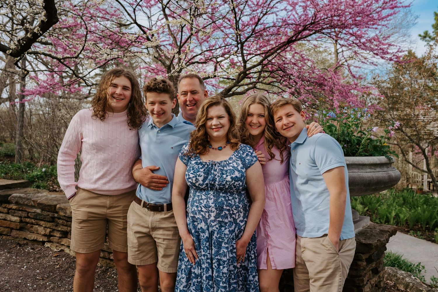 Cherry blossom trees in full bloom create a stunning pink backdrop for springtime family portraits.