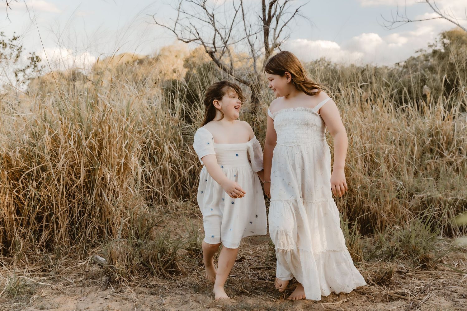 Sisters giggle and walk hand-in-hand during a Brisbane family photo session by Joanna Kate Photography