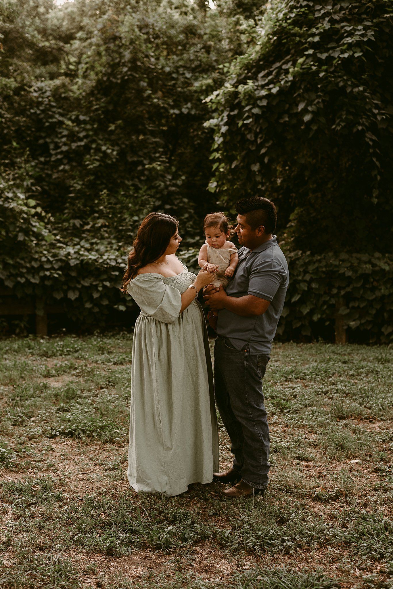 Tender family moment captured during outdoor photo session with natural backdrop.