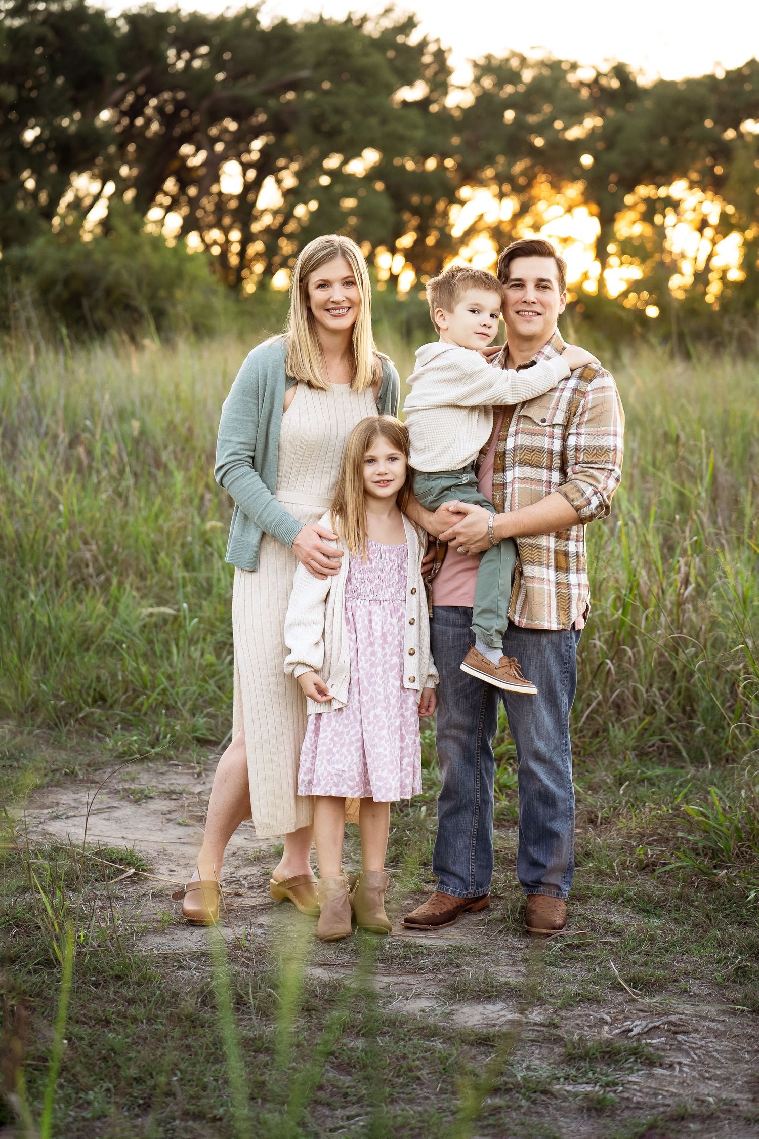 Cibolo Creek Nature Center family of four standing in a field of grass with golden sun
