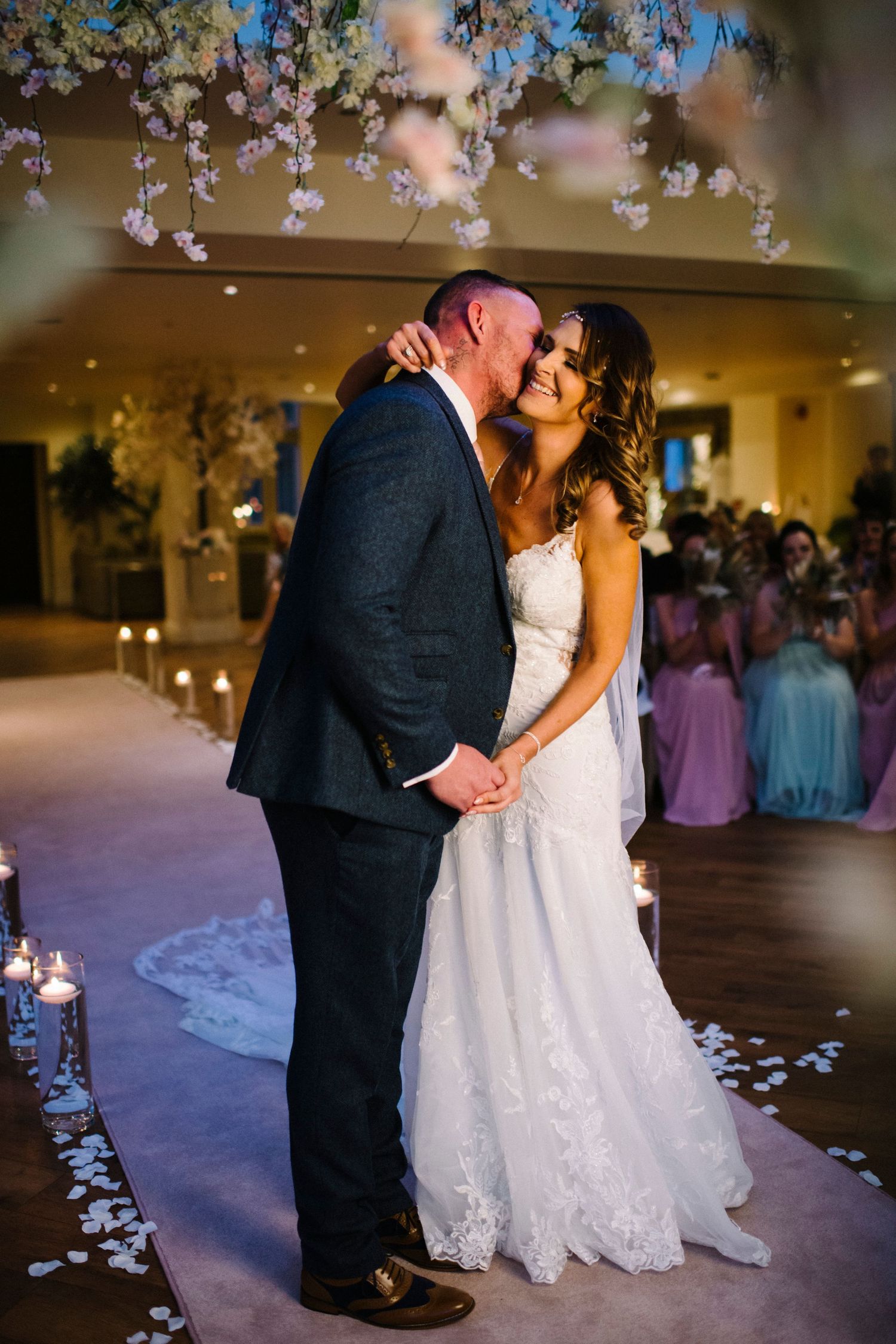 Romantic first dance moment under hanging floral decorations in an elegant ballroom setting.