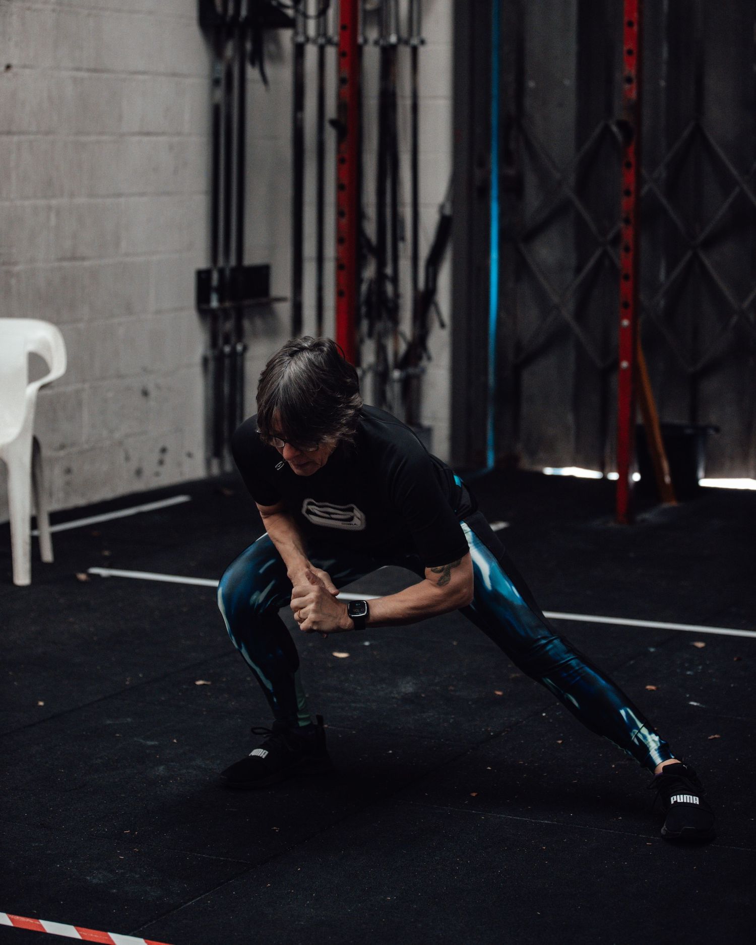 Athlete performing deadlift with heavy weights on barbell in front of red gym wall.