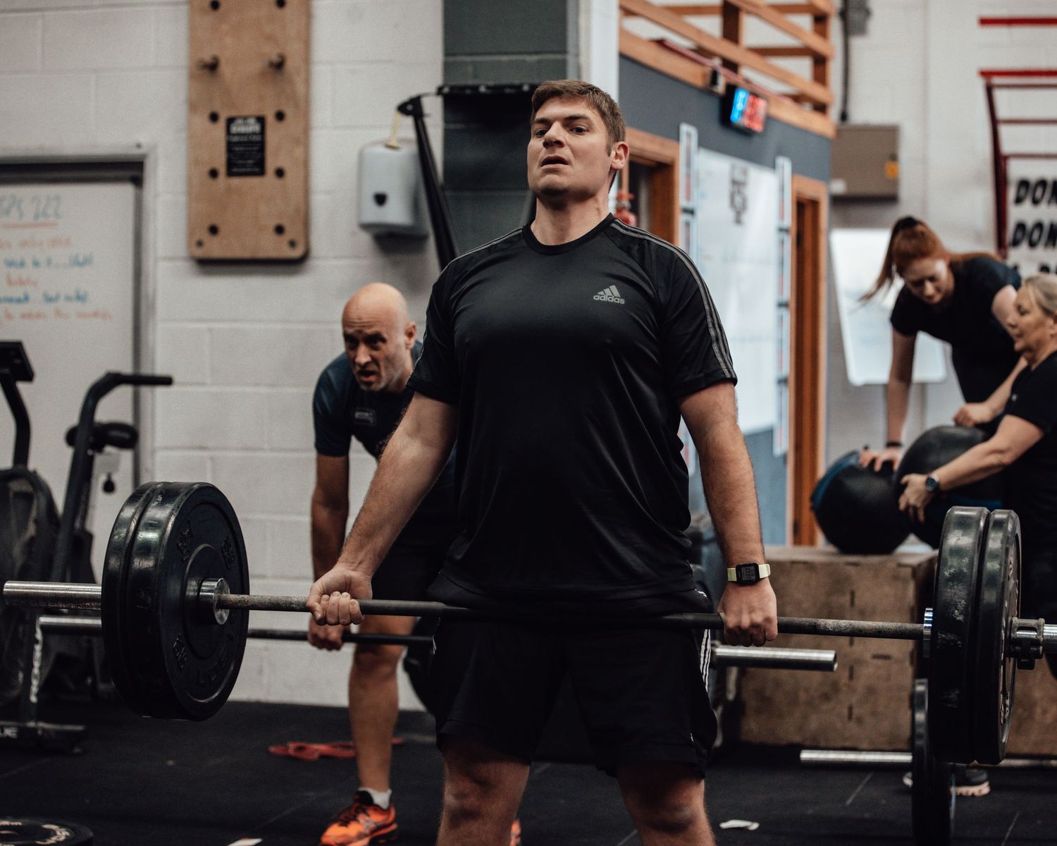Athlete in black workout clothes performing box jump exercise in indoor gym setting.