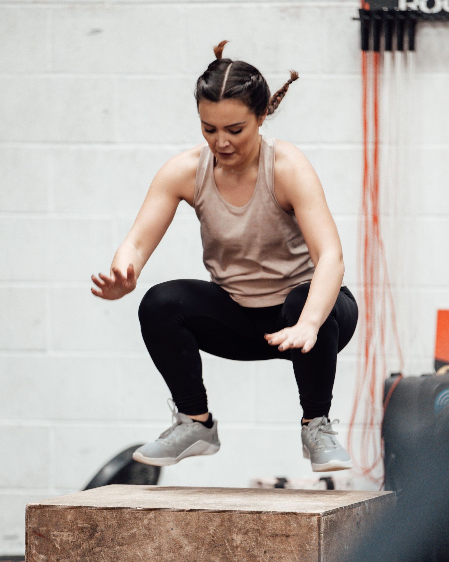 Athlete performing a box jump exercise at a fitness facility.