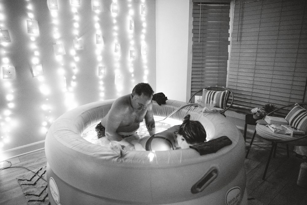 Birth attendants provide care in an inflatable pool with twinkle lights illuminating the background.