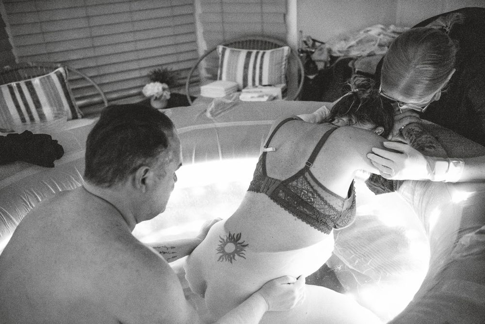 Support team members attend to a laboring person in an inflatable birthing tub.