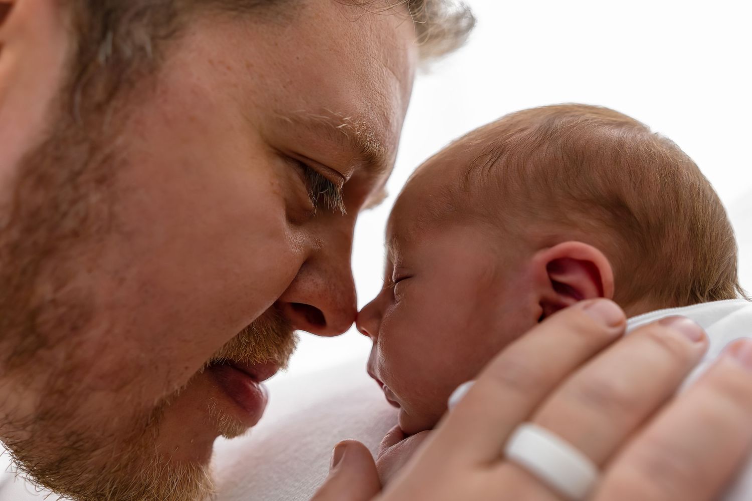Intimate close up portrait of father and infant sharing tender nose-to-nose moment.