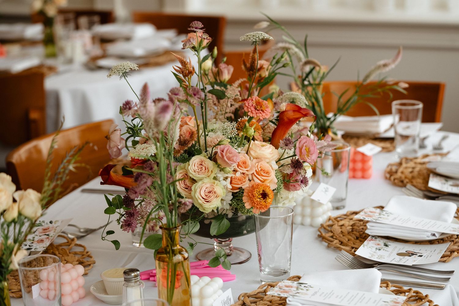 Elegant table settings with woven placemats and floral centerpieces at a celebration.