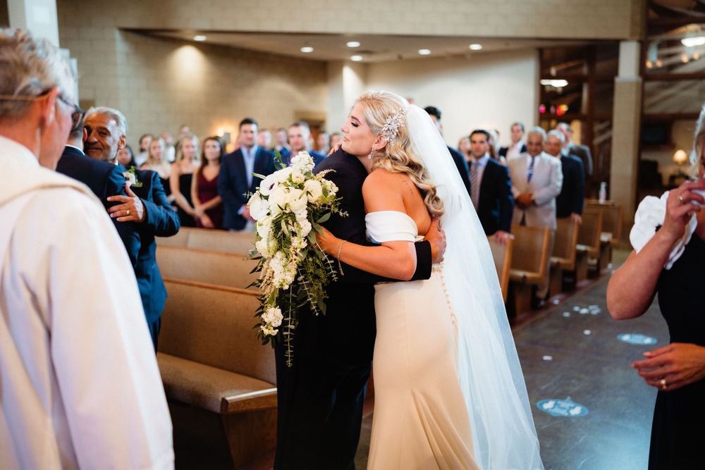 Emotional embrace during wedding ceremony in church sanctuary with guests looking on.