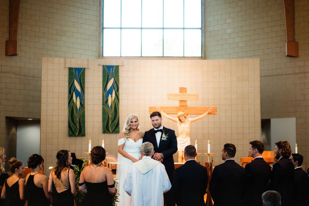 Wedding ceremony in a modern church sanctuary with green banners and wooden decor.