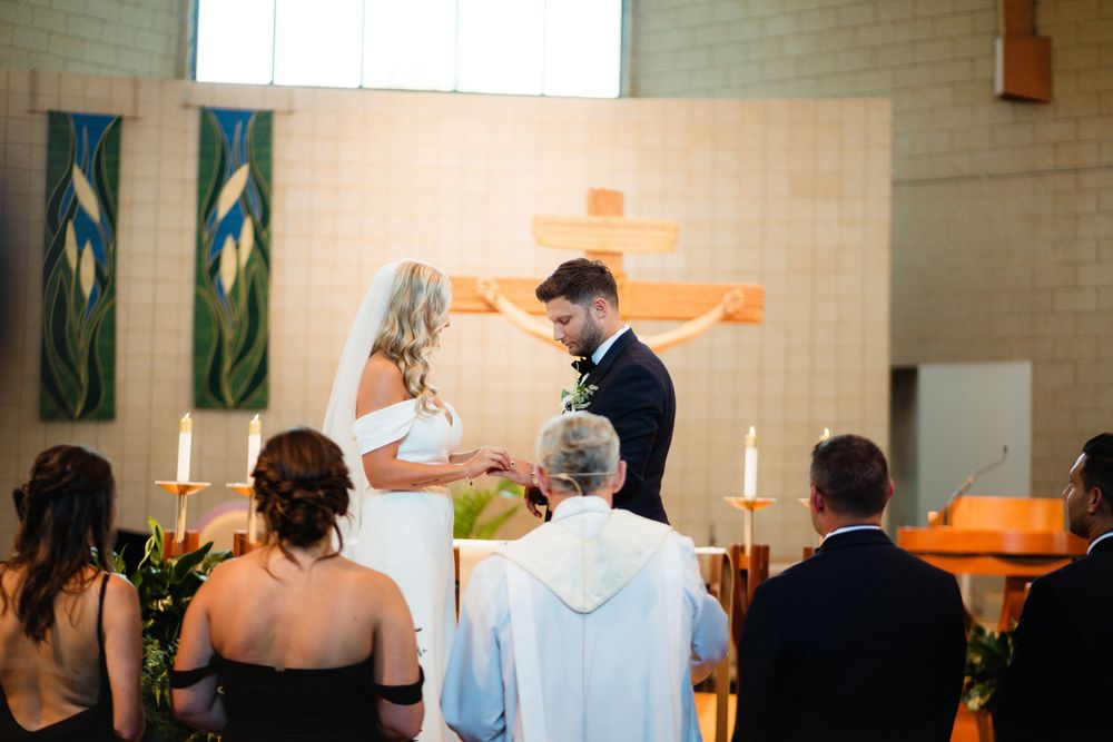 Traditional wedding ceremony taking place at church altar with decorative green banners.