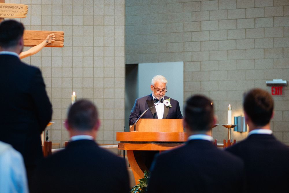 Speaker at podium addresses formal gathering in indoor venue.