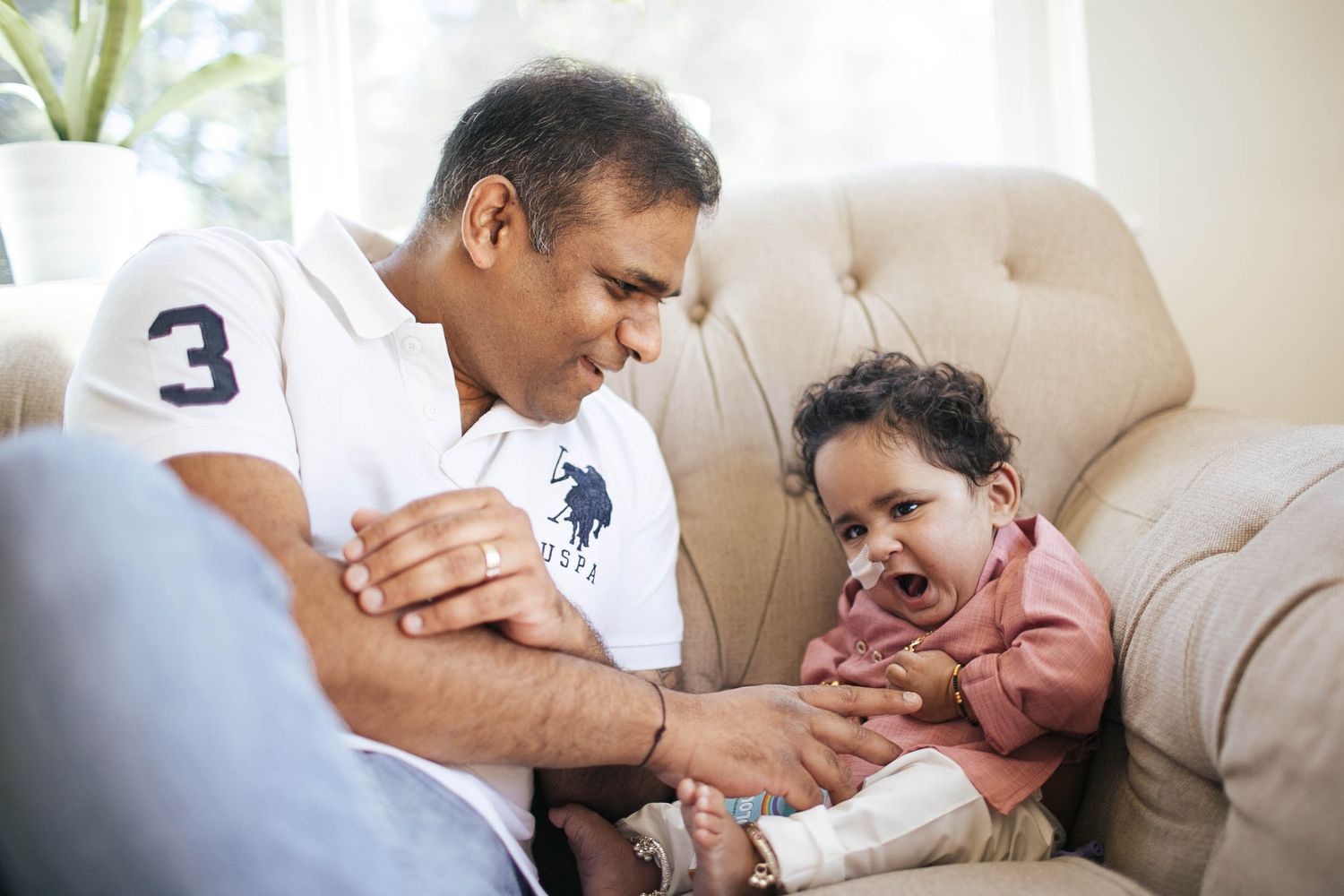 everett lifestyle photographer: a father plays with his son while sitting on a couch at home