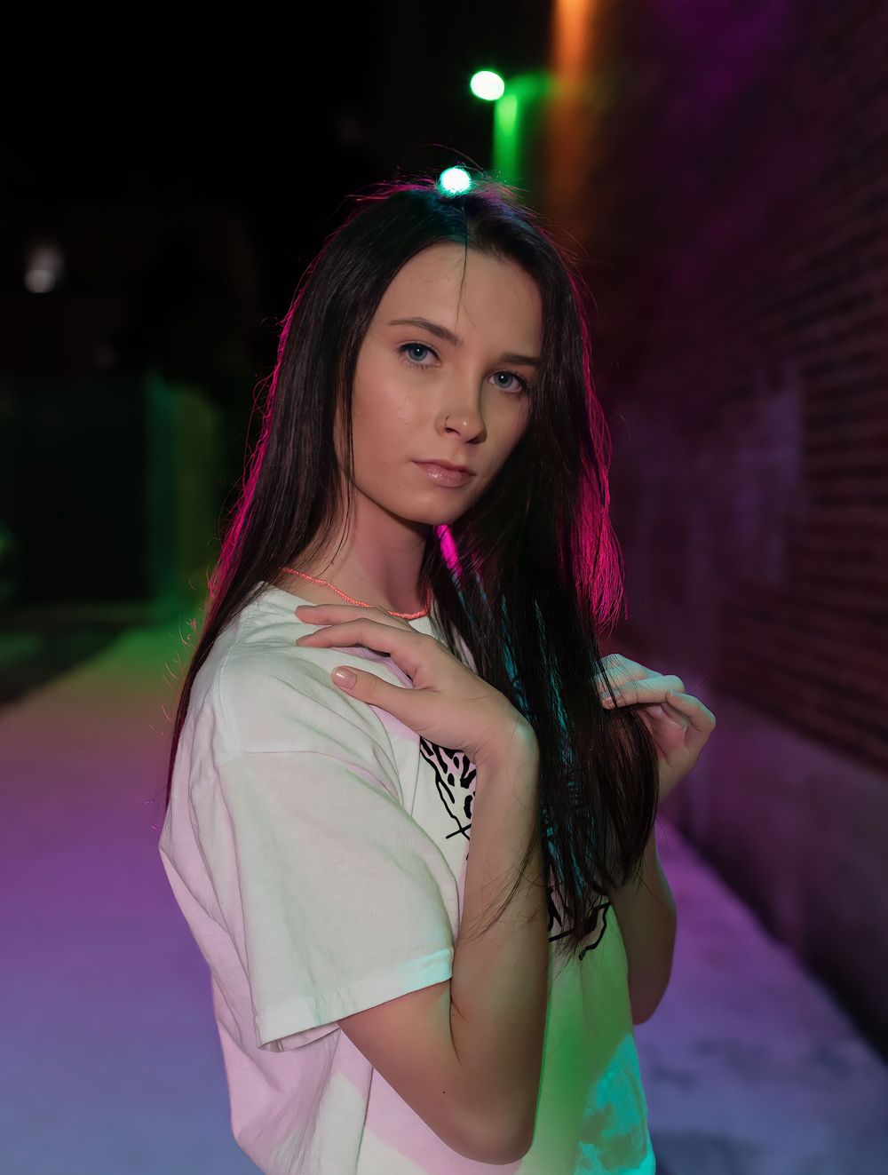 Portrait shot in a dark setting with colorful pink and green lighting effects