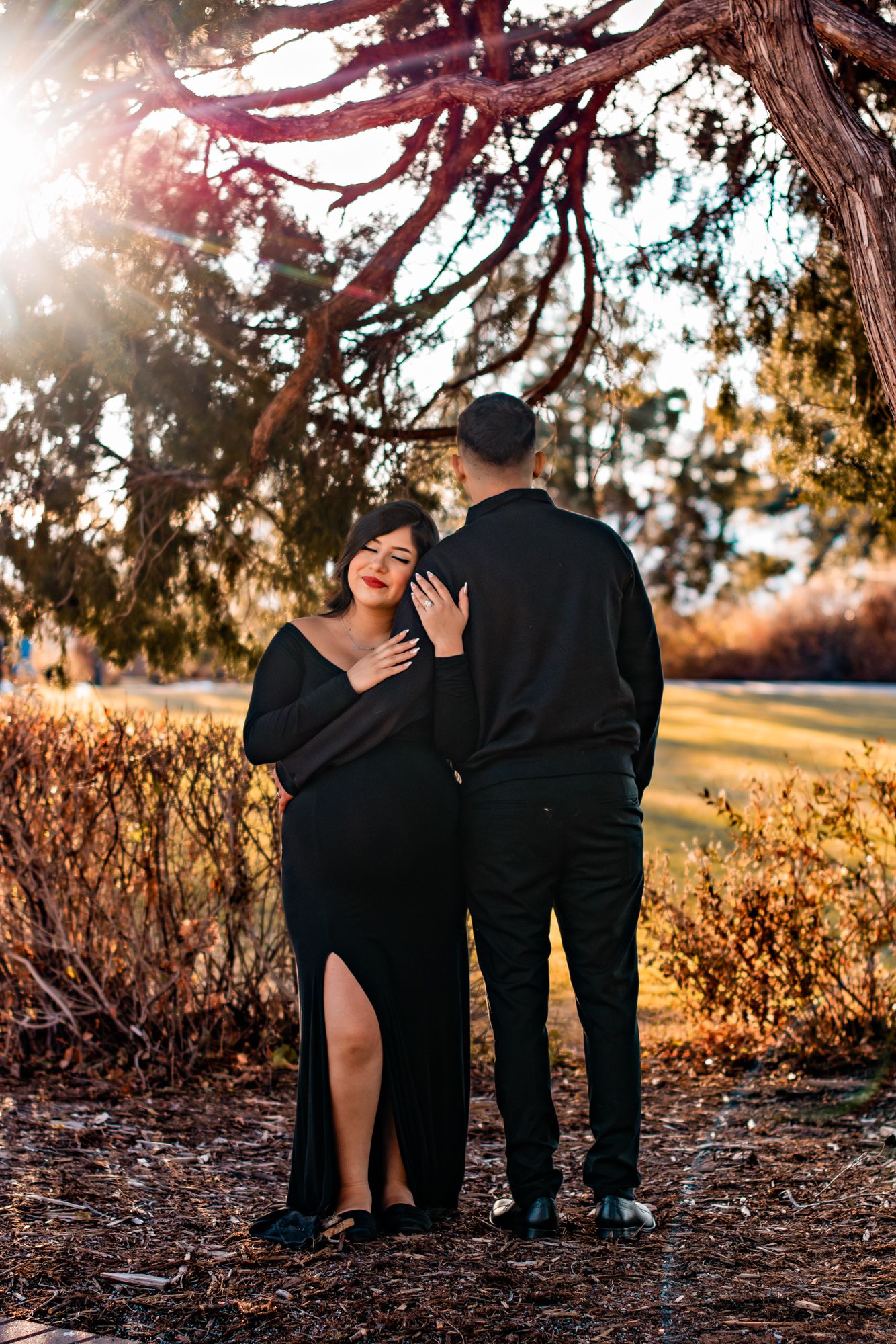 couple posed for maternity photos facing opposite directions at sunset