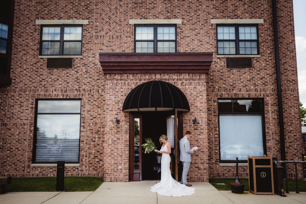 Wedding couple standing in brick building doorway entrance.