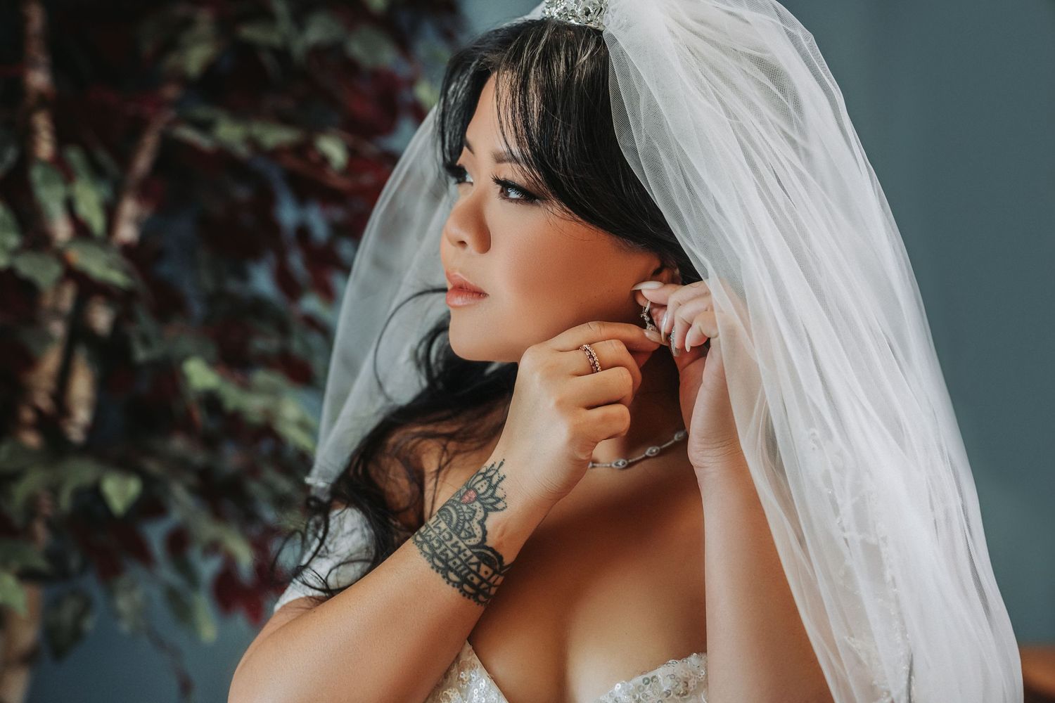 Close-up of bride in lace wedding dress adjusting jewelry.